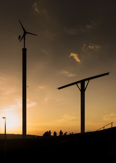 Deutschland, Wuppertal, Bergische Universität Wuppertal, Windrad, Solaranlage und Studenten bei Sonnenuntergang - SKAF00062