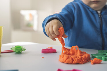 Hand of baby girl taking modeling clay, close-up - MOMF00545