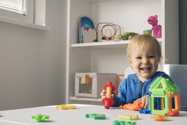 Porträt eines lachenden kleinen Mädchens, das mit Knetmasse im Kinderzimmer spielt - MOMF00550