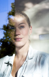 Portrait of smiling woman looking out of window - LMJF00024