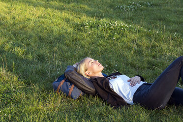 Frau liegt auf einer Wiese im Park und entspannt sich - LMJF00029