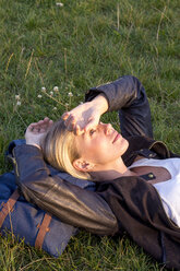 Woman lying on a meadow in a park relaxing - LMJF00030