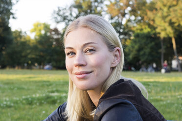 Porträt einer zufriedenen blonden Frau, die sich in einem Park entspannt - LMJF00031