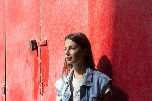 Porträt einer träumenden jungen Frau vor einem roten Hintergrund - LMJF00036