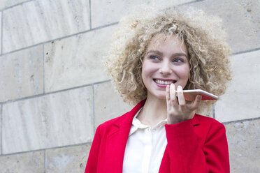 Porträt einer lächelnden blonden Frau mit Locken, die am Telefon spricht - LMJF00045