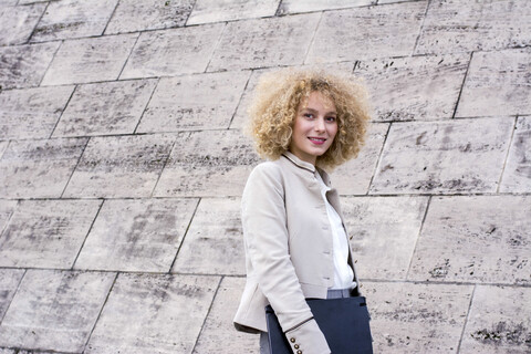 Porträt einer modischen blonden Frau mit einer Mappe, lizenzfreies Stockfoto