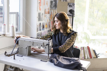 Young designer using sewing machine in an atelier - AFVF02056