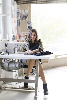 Junge Designerin an der Nähmaschine in einem Atelier - AFVF02057