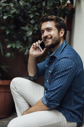 Porträt eines lächelnden Geschäftsmannes am Telefon im Freien - BOYF01081