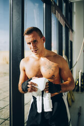 Portrait of boxer preparing to fight holding boxing glove - OCMF00134