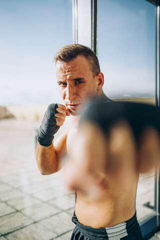 Porträt eines Boxers mit Bandagen beim Boxen am Fenster, lizenzfreies Stockfoto