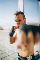 Portrait of boxer wearing bandages boxing at the window - OCMF00137