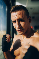 Porträt eines selbstbewussten Boxers mit Bandagen am Fenster - OCMF00138