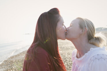 Zärtliches lesbisches Paar küsst sich am sonnigen Strand - CAIF22254