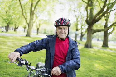 Porträt selbstbewusster aktiver älterer Mann auf dem Fahrrad im Park - CAIF22261