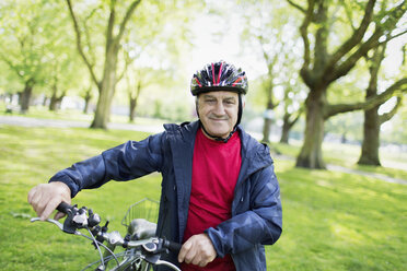 Portrait confident active senior man riding bike in park - CAIF22261