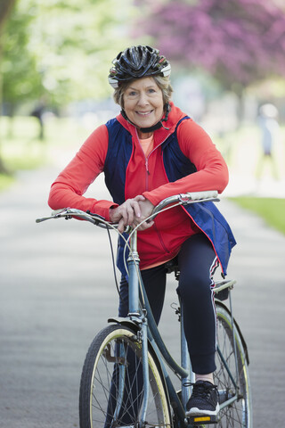 Porträt einer lächelnden, selbstbewussten, aktiven älteren Frau beim Radfahren im Park, lizenzfreies Stockfoto