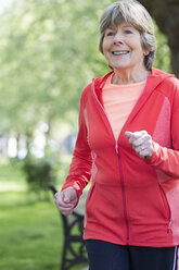 Smiling active senior woman running in park - CAIF22279