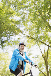 Portrait confident active senior man riding bike in park - CAIF22293