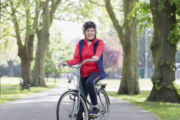Portrait confident active senior woman riding bike in park - CAIF22296