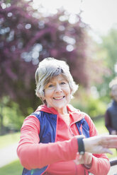 Portrait smiling, confident active senior woman checking smart watch in park - CAIF22299