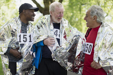 Aktive ältere Männer, die in Wärmedecken eingewickelt ein Sportrennen beenden - CAIF22306