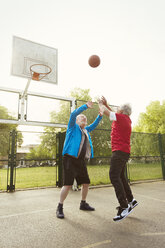 Active senior men friends playing basketball in park - CAIF22318