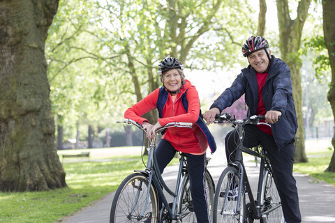 Porträt lächelndes, selbstbewusstes, aktives Seniorenpaar beim Radfahren im Park, lizenzfreies Stockfoto