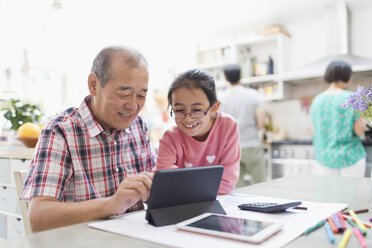 Großvater und Enkelin benutzen ein digitales Tablet in der Küche - CAIF22344