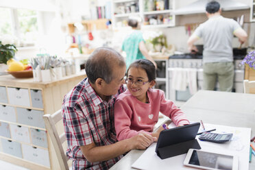 Großvater und Enkelin benutzen ein digitales Tablet am Küchentisch - CAIF22347