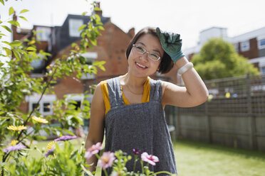 Portrait smiling woman gardening in sunny yard - CAIF22350