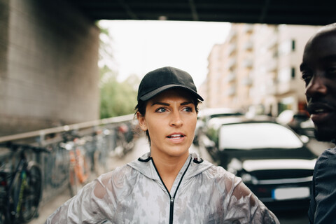 Sportlerin im Gespräch mit Sportler auf dem Bürgersteig in der Stadt, lizenzfreies Stockfoto