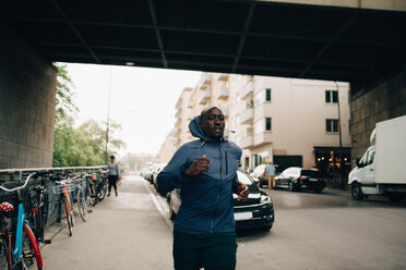 Männlicher Sportler joggt auf dem Bürgersteig in der Stadt - MASF09876