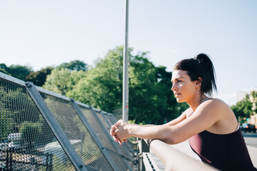 Seitenansicht einer erschöpften Sportlerin, die sich am Geländer einer Brücke anlehnt - MASF09926