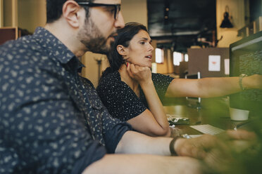 Female computer programmer with colleague discussing over coding in office - MASF09954