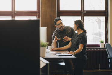 Mid adult businessman discussing new plan with female colleague in office - MASF09960