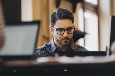 Businessman wearing glasses while working in creative office - MASF09964