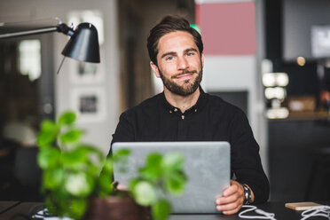 Portrait of confident creative businessman sitting at desk in office - MASF09967