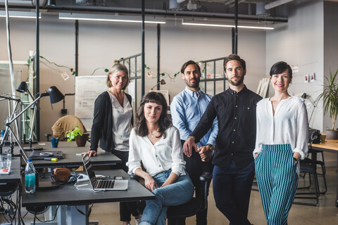 Portrait of confident coworkers by desk in creative office stock photo