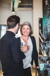 Business people talking while standing by coffee maker at office cafeteria - MASF10005