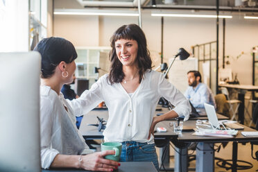 Female coworkers talking while standing at counter in office - MASF10012