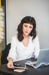 Creative businesswoman using mobile phone while sitting at desk in office - MASF10045