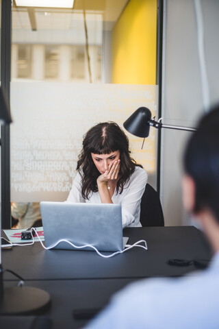 Kreative Geschäftsfrau mit Laptop am Schreibtisch im Büro, lizenzfreies Stockfoto