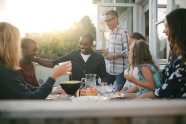 Fröhliche Mehrgenerationenfamilie beim Mittagessen auf der Veranda - MASF10076