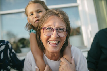 Glückliche ältere Frau nimmt ihre Enkelin auf der Veranda huckepack - MASF10085
