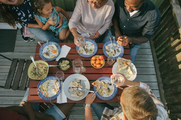 Blick von oben auf eine Mehrgenerationenfamilie beim Mittagessen am Tisch auf der Veranda - MASF10088