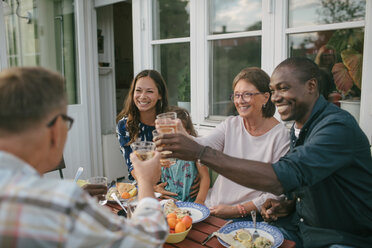 Glückliche Mehrgenerationen-Familie stößt bei einer Gartenparty am Tisch mit Getränken an - MASF10091