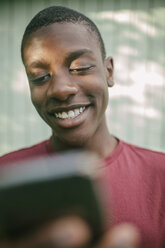 Lächelnder Junge benutzt Handy im Hinterhof - MASF10095