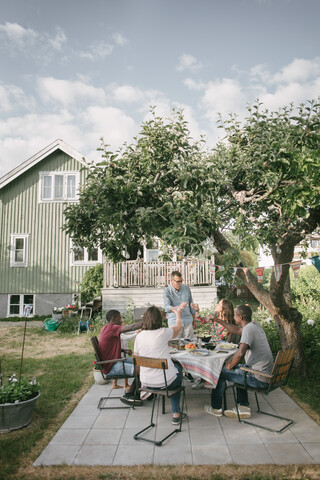 Mehrgenerationen-Familie stößt während einer Gartenparty auf der Terrasse mit Getränken an, lizenzfreies Stockfoto