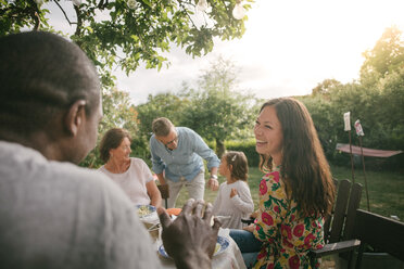 Mittlere erwachsene Frau lächelt beim Mittagessen am Tisch während einer Gartenparty - MASF10110